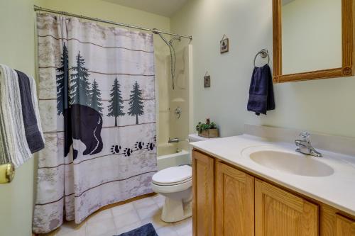 a bathroom with a shower curtain with a toilet and a sink at Hot Tub and Game Room Cozy Big Bass Lake Home! in Gouldsboro