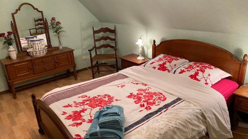 a bedroom with a bed with red flowers on it at Villa Lucienne in Comines