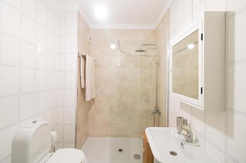 La salle de bains blanche est pourvue de toilettes et d'un lavabo. dans l'établissement Mar Azul, à Praia da Barra
