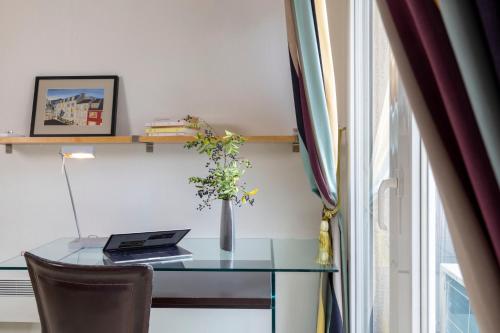 a glass table with a laptop and a vase on it at Maison Lavaud in Paris