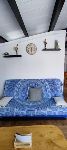 a bed with a blue blanket and a clock on a wall at ATICO Loli in Berga