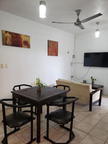 ein Wohnzimmer mit einem Tisch und Stühlen sowie einem Flachbild-TV in der Unterkunft La azul bonita in Chetumal