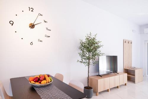 a table with a bowl of fruit and a clock on the wall at True Home in Sfakerá