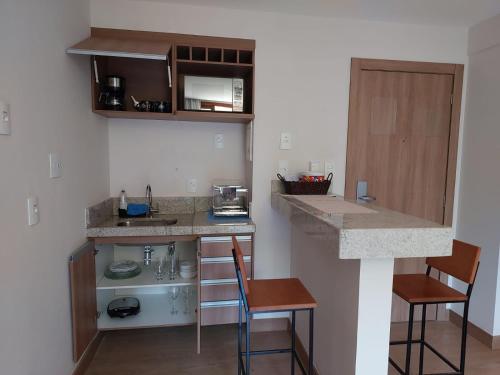 a small kitchen with a counter and two chairs at Flat Hotel Pedra Azul in Pedra Azul