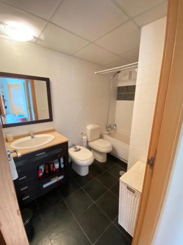 een badkamer met een wastafel, een toilet en een spiegel bij Apartamento Benidorm con piscina en la playa in Cala de Finestrat