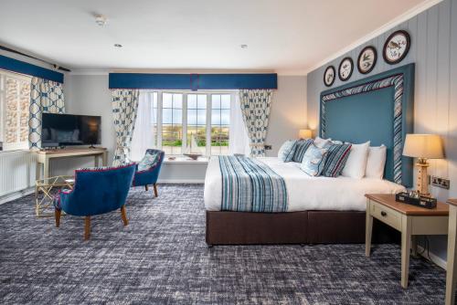 Habitación de hotel con cama grande y TV en The Manor Coastal Hotel & Inn, Blakeney, Norfolk, en Blakeney