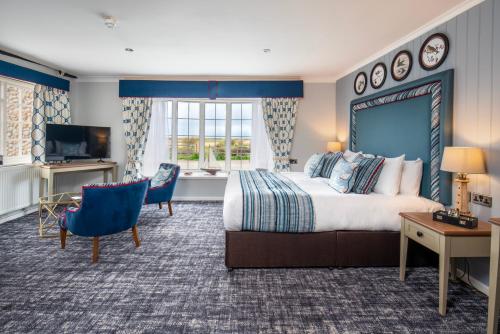 a hotel room with a large bed and a television at The Manor Coastal Hotel & Inn, Blakeney - part of The Coaching Inn Group in Blakeney