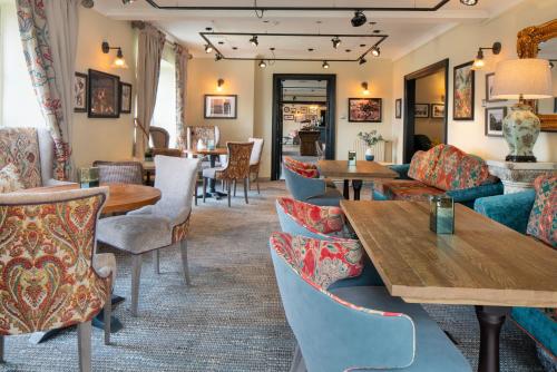 una sala d'attesa con tavoli, sedie e una tavola di The Manor Coastal Hotel & Inn, Blakeney, Norfolk a Blakeney