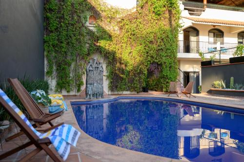 una piscina en un patio con sillas y un edificio en Villa Cobojo en Bucerías