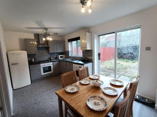 a kitchen with a wooden table with chairs and a dining room at Trevithick Gardens, No 47. in Merthyr Tydfil