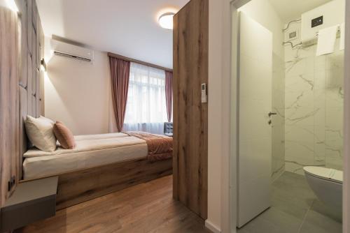 uma casa de banho com uma cama, um chuveiro e um WC. em Casa ARTEE Free Parking em Sarajevo