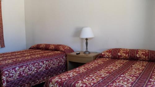 a hotel room with two beds and a lamp on a table at Lido Hotel in Huntington Park