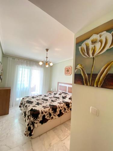カーラ・デ・フィネストラットにあるApartamento Benidorm con piscina en la playaのベッドルーム1室(花の絵が飾られたベッド1台付)