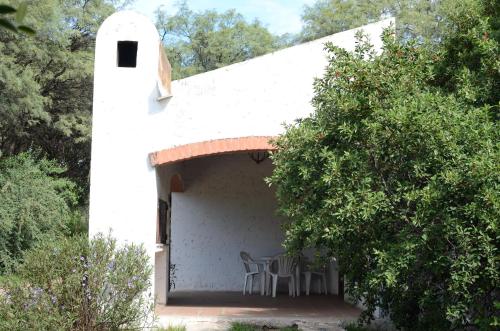 un edificio blanco con mesa y sillas en Hospedajes Serranos, Cabañas Aaron, solo acepto reservas por privado en Villa Las Rosas