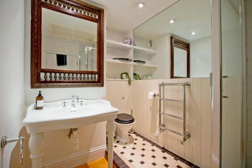 ein Bad mit einem Waschbecken, einer Dusche und einem Spiegel in der Unterkunft 4 Bed Duplex Garden Views in London