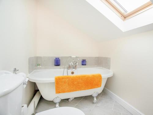 a white bathroom with an orange towel on a tub at Stargazer - Uk43267 in Luppitt