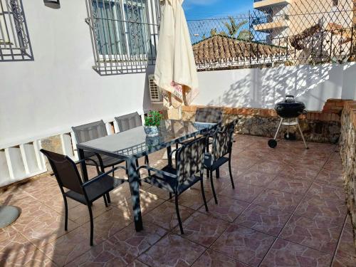 un patio con mesa, sillas y parrilla en Villa Musica, en Torremolinos