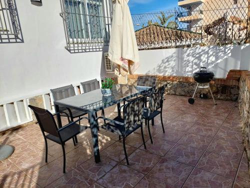 een terras met een tafel en stoelen en een barbecue bij Villa Musica in Torremolinos