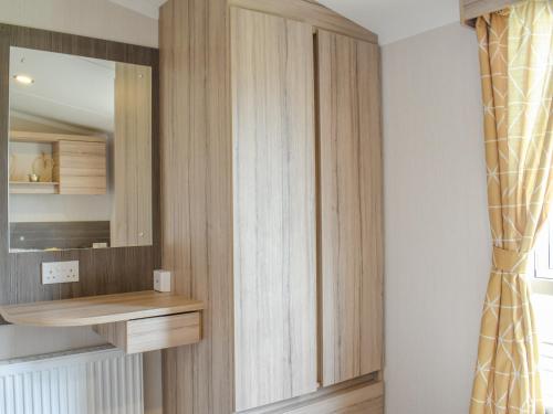 a dressing room with wooden cabinets and a mirror at Seaview 1 in Heysham