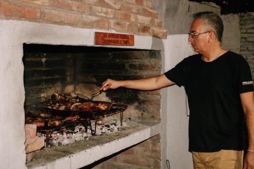 a man is cooking chickens in a brick oven at SIGRUM Hostel in San Rafael