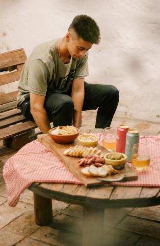 a man sitting on a bench with a table with food at SIGRUM Hostel in San Rafael