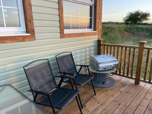 two chairs and a grill on the porch of a house at Keepers Shepherd hut with Hot Tub in Whitby