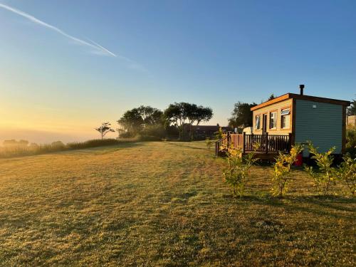 a tiny house in a field with the sun setting at Keepers Shepherd hut with Hot Tub in Whitby