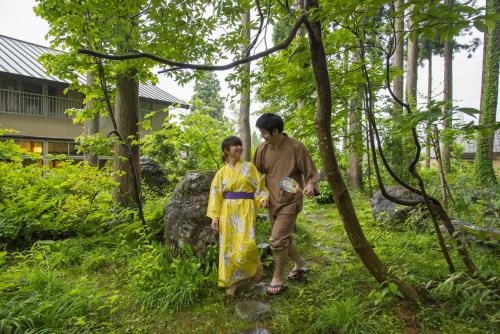 a man and a young girl walking through a forest at Ichirino Kogen Hotel Roan in Hakusan