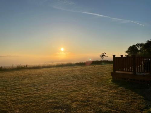 a bench in a field with the sunset in the background at Keepers Shepherd hut with Hot Tub in Whitby