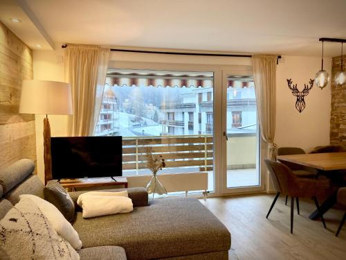 a living room with a couch and a large window at Spacious 3 Room Apartment - Family-Friendly - Central Leukerbad - Great Views in Leukerbad