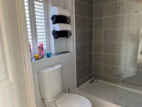 a bathroom with a toilet and a shower with towels at Cathedral Coach House - Lichfield in Lichfield