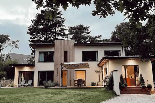 una grande casa bianca con un prato davanti di Chambre indépendante avec sdb et toilettes privées dans une maison en forêt proche du golf et de la plage Entree indépendante avec acces privé a Le Touquet-Paris-Plage