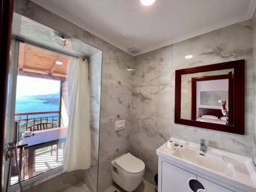 La salle de bains est pourvue d'un lavabo, de toilettes et d'une fenêtre. dans l'établissement Argileos Rooms, à Himarë