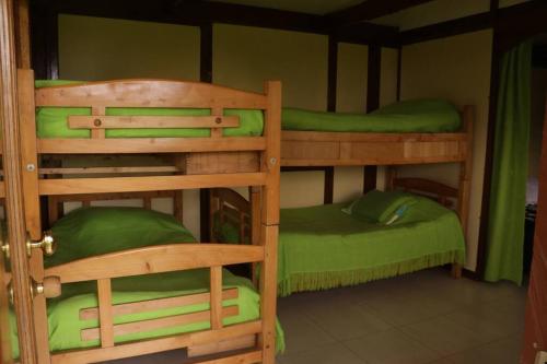 two bunk beds in a room with green sheets at Cabaña Villa Esperanza in Santandercito