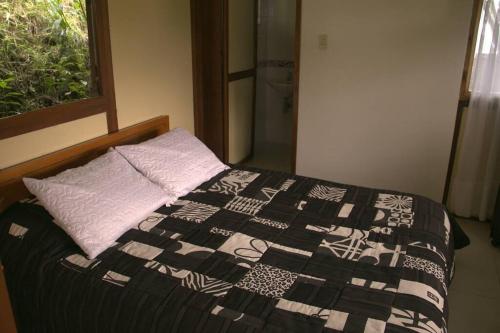 a bed with a black and white quilt and a window at Cabaña Villa Esperanza in Santandercito