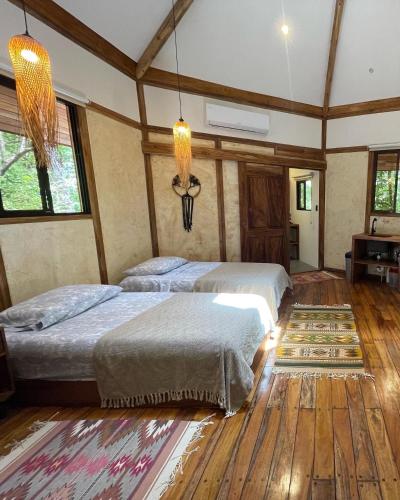 2 camas num quarto com pisos e janelas em madeira em Casita Ylang Ylang em Nosara