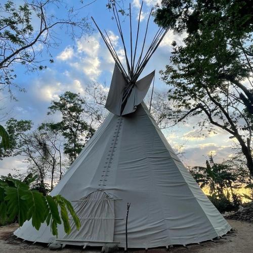 a white teepee tent with trees in the background at Casita Ylang Ylang in Nosara