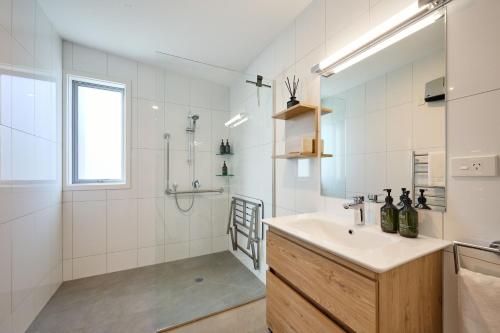 La salle de bains blanche est pourvue d'un lavabo et d'une douche. dans l'établissement Shearwater Apartments, à Kaikoura