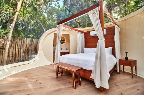 a bedroom with a canopy bed and a wooden floor at Astral Tulum in Tulum