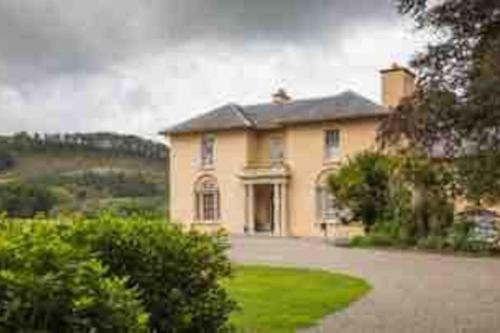 a large yellow house with a large driveway at Y Villa Môr in Llanarth