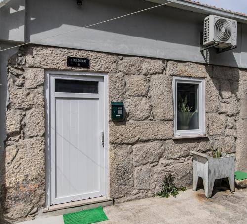 ein Steingebäude mit einer weißen Tür und einem Fenster in der Unterkunft Casa das Virtudes - Estadia no coração do Porto, Lapa in Porto