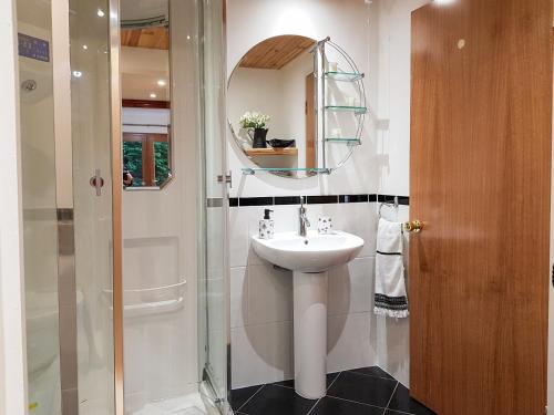 a bathroom with a sink and a shower with a mirror at The Old Post Office On Loch Tay in Stron-fearnan