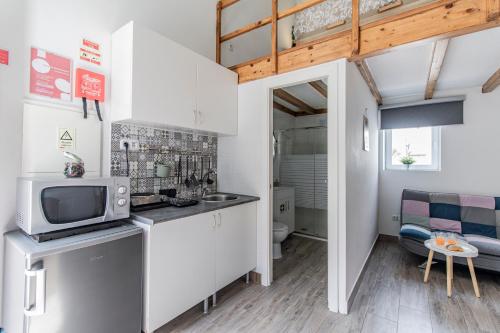 eine kleine Küche mit weißen Schränken und einer Mikrowelle in der Unterkunft Casa das Virtudes - Estadia no coração do Porto, Lapa in Porto