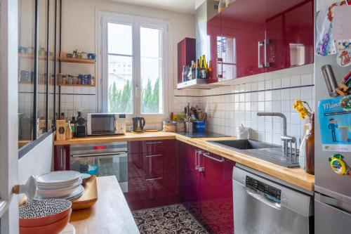 a kitchen with red cabinets and a sink at Chambre - Marceau in Courbevoie