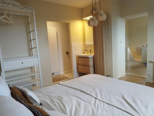 1 dormitorio con cama blanca y lavamanos en Au pied du mur en Huy