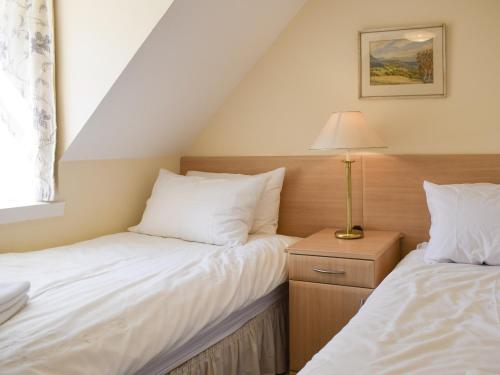 a bedroom with two beds and a lamp on a night stand at Oak Cottage - Uk43458 in Killin