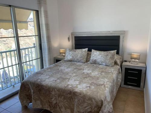 a bedroom with a bed with two lamps and a window at Las Brisas de Puerto Rico in Mogán