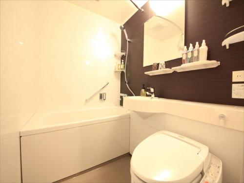 a white bathroom with a toilet and a sink at Centurion Hotel Ikebukuro Station in Tokyo