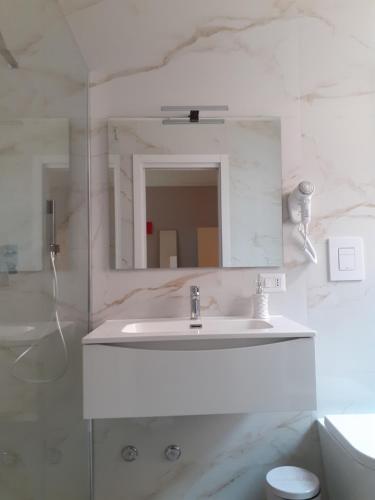 a white bathroom with a sink and a mirror at Sweet Suite Margherita in Margherita di Savoia