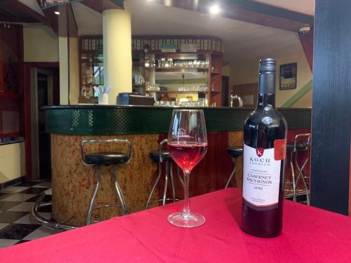 a bottle of wine sitting on a table with a glass at Várfal Wellness Panzió in Pécs